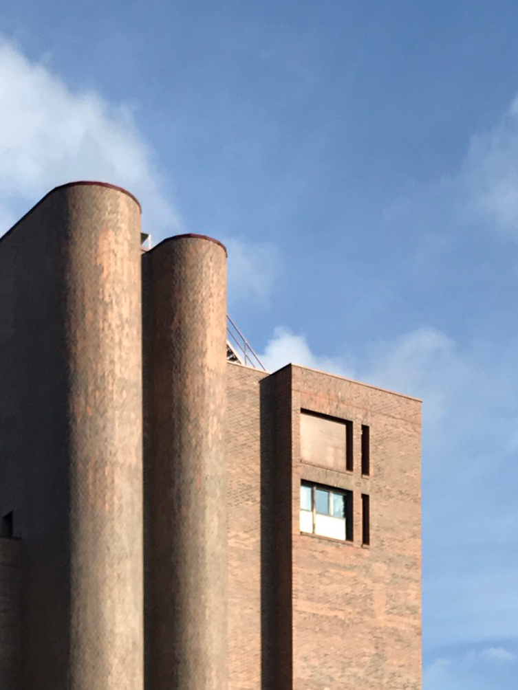 Facade of a modernist building by architect Juan Daniel Fullaondo, featuring cylindrical brick columns and minimalist design.